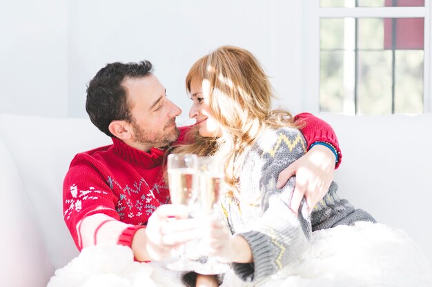 Festive happy couple with champagne on sofa