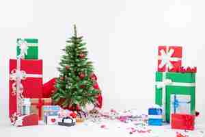 Free photo festive holiday mood with santa claus hiding behind decorated xsmas tree on white background