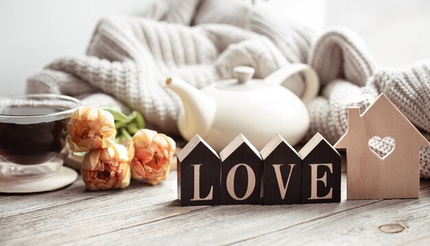 Festive home still life with flowers, a cup of tea and decor details on a wooden surface close up.