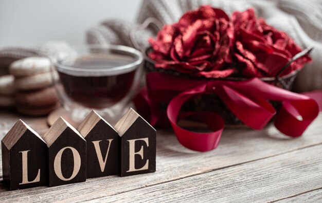 Festive home still life with wooden word love, a cup of tea and flowers