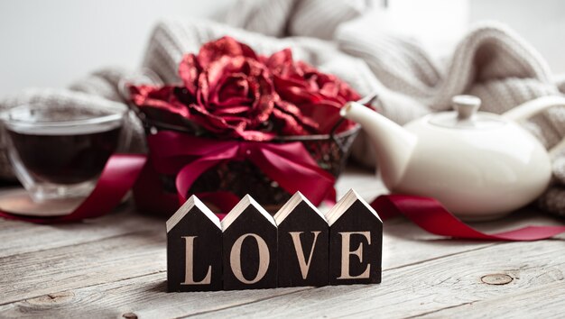 Festive home still life with wooden word love, a cup of tea and a teapot