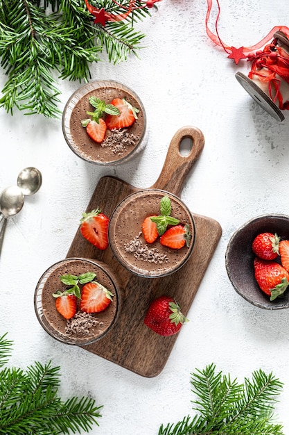 Free photo festive homemade delicious chocolate mousse or panna cotta with berries on a white stone background vertical