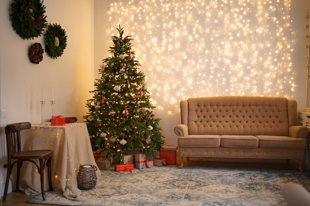 Festive interior with comfortable sofa and decorated Christmas tree