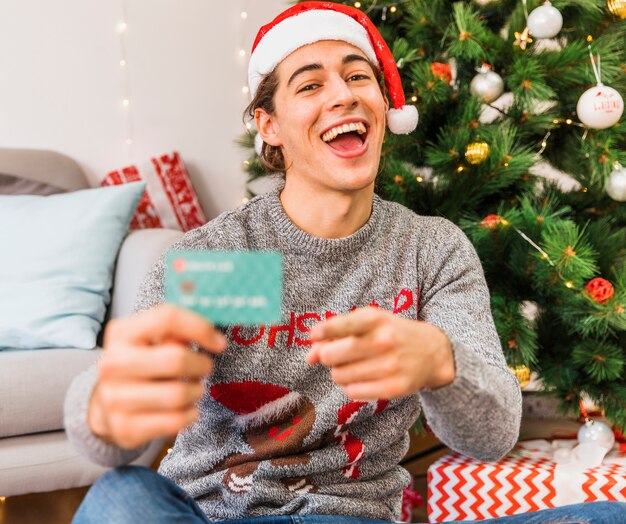 Festive man pointing at credit card 