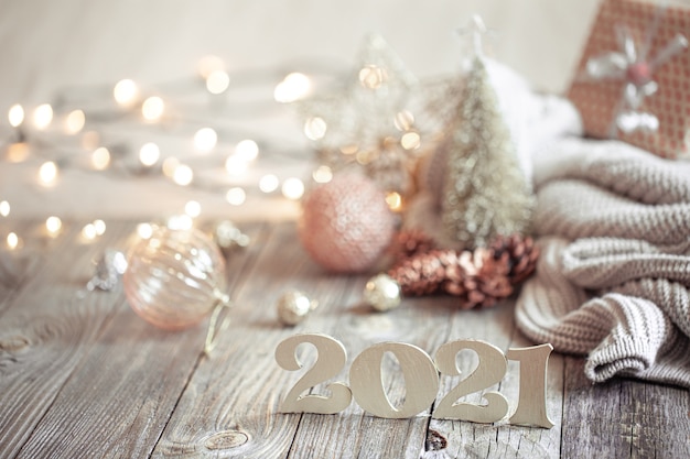Festive new year composition with wooden new year number on a light blurred background with christmas decoration.