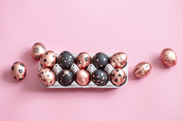 Праздничная роспись золотыми и черными пасхальными яйцами на розовом.