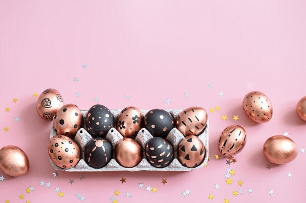 Праздничная роспись золотыми и черными пасхальными яйцами на розовом.