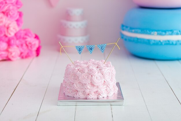 Festive pink rose ombre cream cake on big blue macaroon. First year cake smash.