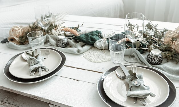 Сервировка праздничного стола дома со скандинавскими декоративными деталями крупным планом.