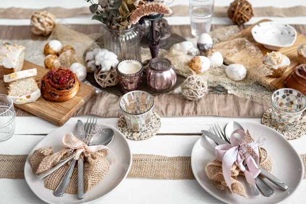 A festive table with beautiful dishes, decorative items and pastries. Easter table setting design idea.