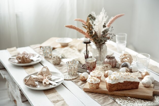 A festive table with a beautiful setting, decorative details, eggs and Easter cake.