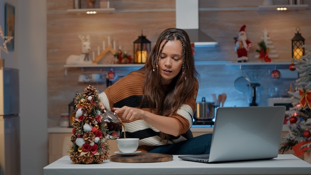 Festive woman talking on video call using laptop