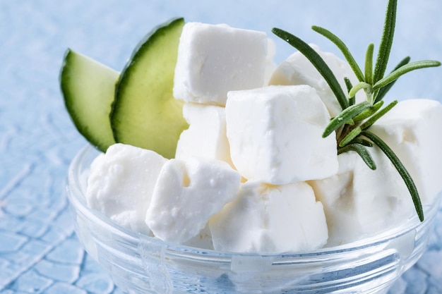 Feta cheese cucumber and herbs in a bowl on blue background