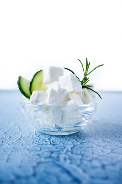 Feta cheese cucumber and herbs in a bowl on blue background