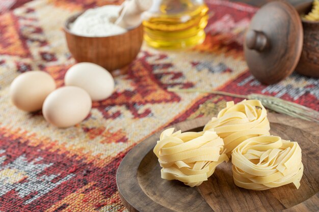 Fettuccine Italian pasta on wooden board with eggs and flour 