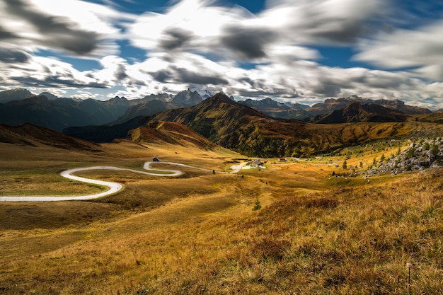 Free photo field surrounded by rocks covered in greenery under the sunlight and clouds