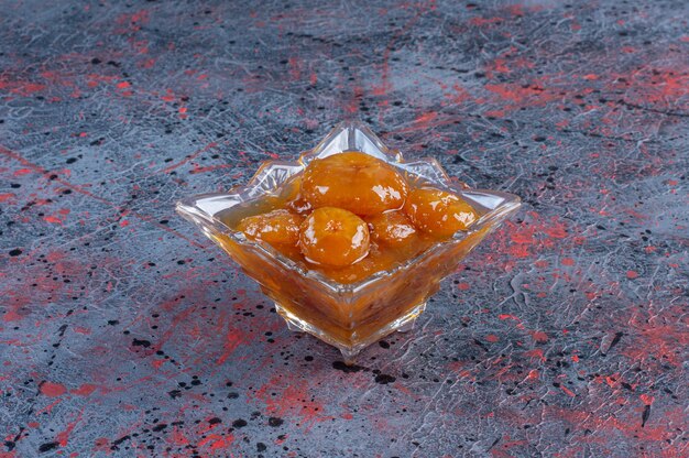 Fig confiture in a glass cup on blue background. 