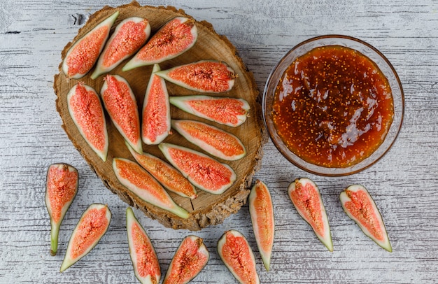 Fig jam with figs in a bowl on grungy and wooden board, flat lay.