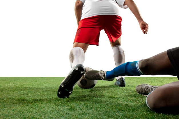 Foto gratuita combattimento. chiudere le gambe di calcio professionista, giocatori di calcio in lotta per la palla sul campo isolato sulla parete bianca. concetto di azione, movimento, emozione ad alta tensione durante il gioco. immagine ritagliata.