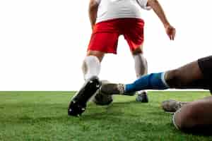 Free photo fighting. close up legs of professional soccer, football players fighting for ball on field isolated on white wall. concept of action, motion, high tensioned emotion during game. cropped image.
