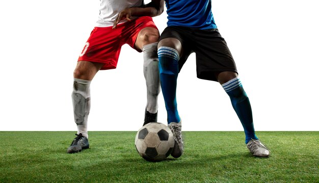 Fighting. Close up legs of professional soccer, football players fighting for ball on field isolated on white wall. Concept of action, motion, high tensioned emotion during game. Cropped image.