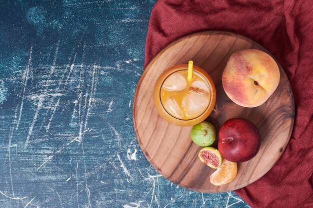 Figs and peach with a cup of drink on blue.