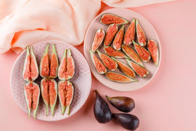 Figs in plates flat lay on pink and textile