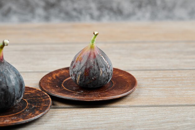 Figs on small plate and on wooden table.