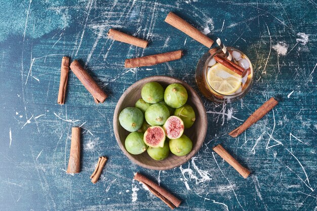 Figs and spices with a cup of drink on blue.