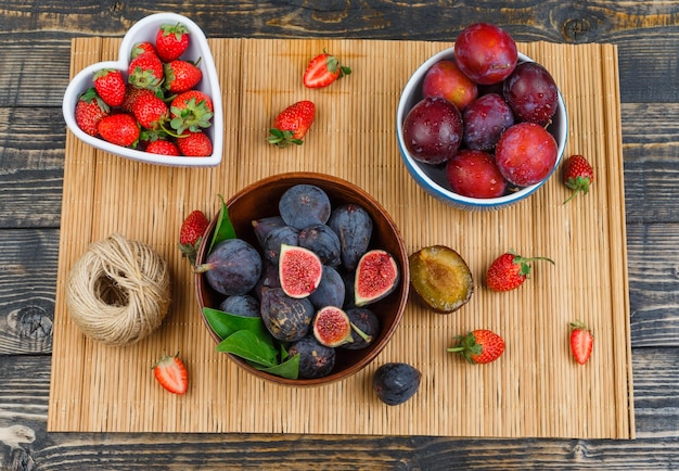 Figs, strawberries and plums on wooden table