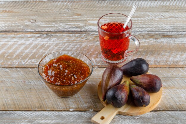 Figs with cup of tea, fig jam high angle view on wooden and cutting board