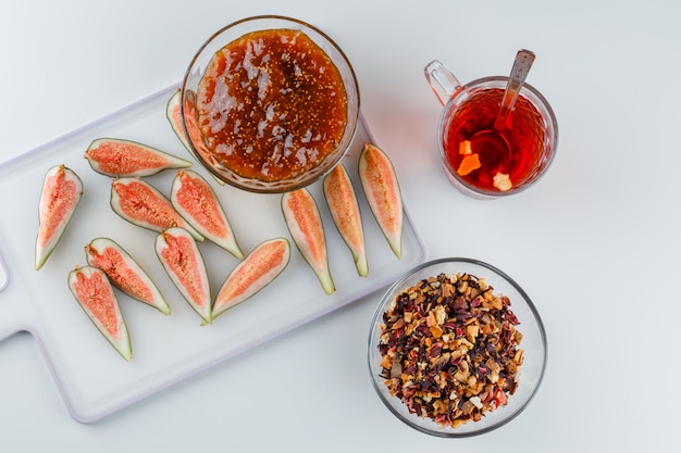 Figs with fig jam, tea, teaspoon, dried herbs top view on white and cutting board