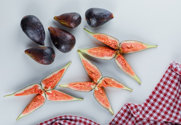 Figs with slices on white and kitchen towel, flat lay.