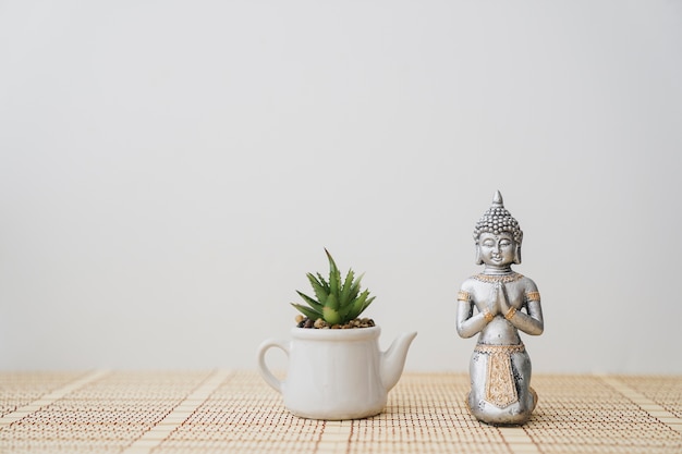 Figure of buddha next to a pot