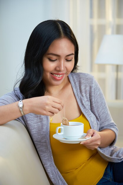 Filipino woman dipping tea bag in cup