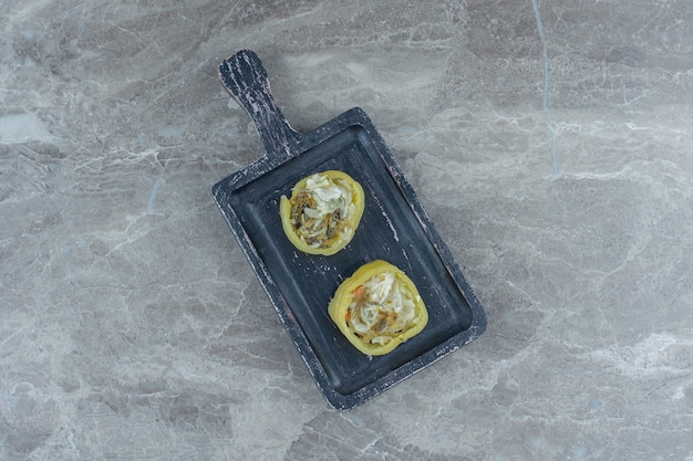 Filled green peppers on wooden cutting board. Top view.