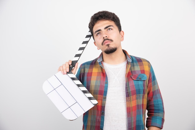 Free photo filmmaker with a clapper board looks thoughtful.