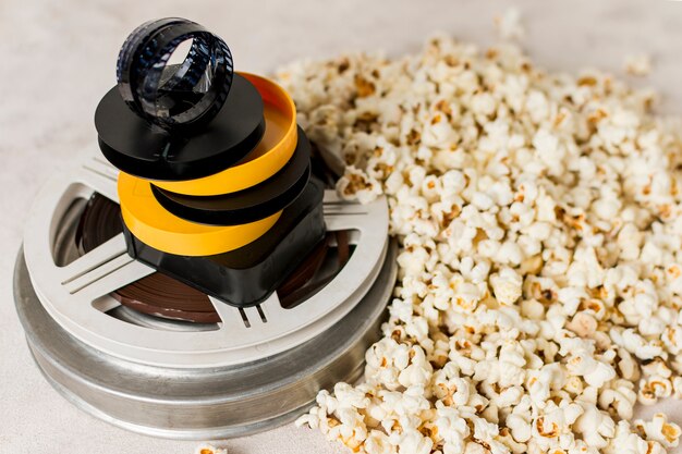 Filmstrip on yellow and black case over the movie film reel with popcorns