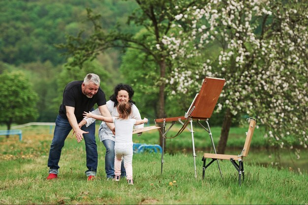 Finally we met. Grandmother and grandfather have fun outdoors with granddaughter. Painting conception
