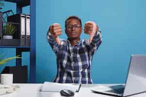 Free photo finance department displeased team leader giving thumbs down to employee. dissatisfied african american agency manager making disapproval gesture because of unfit marketing strategy of startup project