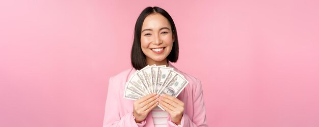 Finance microcredit and people concept happy smiling asian businesswoman showing dollars money stand