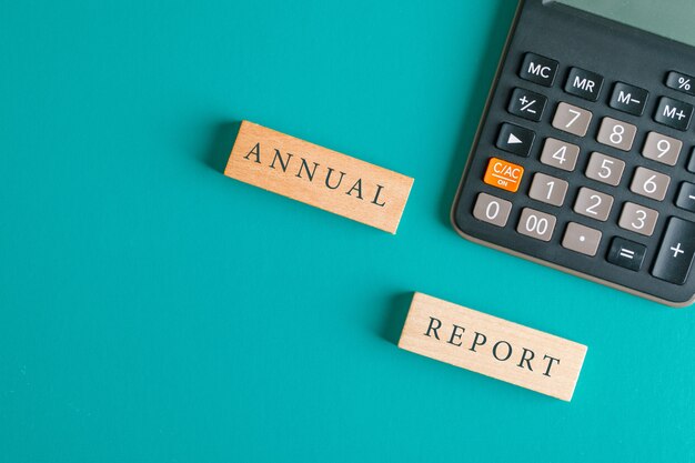 Financial accounting concept with wooden blocks, calculator on turquoise table flat lay.