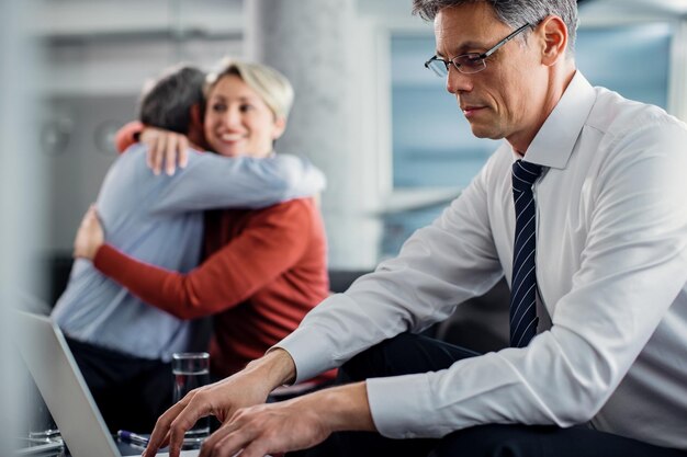 Financial advisor working on laptop while having a meeting with clients in the office