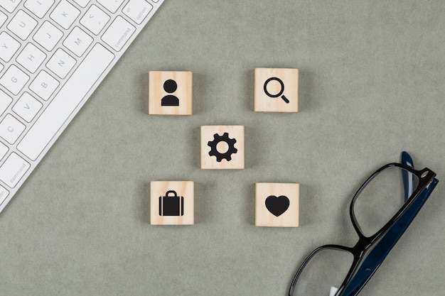 Financial concept with wooden cubes, glasses, keyboard on grey background flat lay.