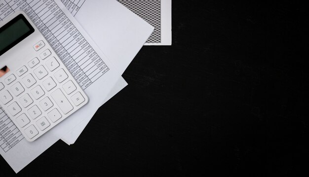 Financial Documents And White Calculators On Black Wooden Desks