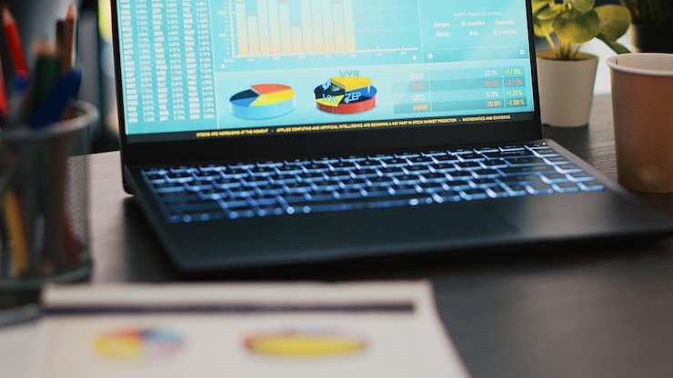 Free Photo financial report on desk next to laptop showing marketing statistics in office