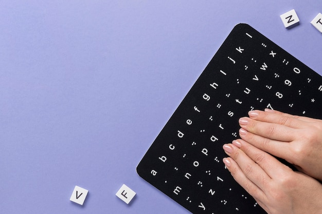 Fingers touching braille alphabet board top view