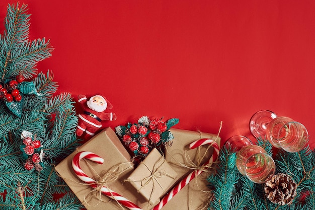 Fir branch, gift box and two glasses of champagne on red background