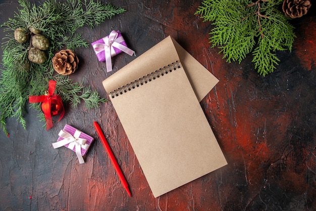 Fir branches a cup of black tea decoration accessories and gift next to notebook with pen on dark background horizontal view