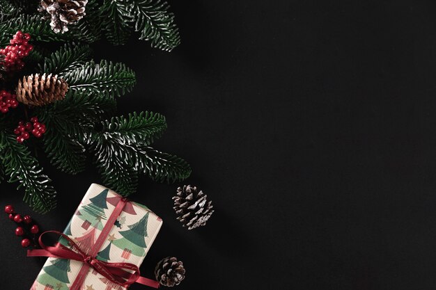 黒の背景にクリスマスプレゼントとモミの木の枝